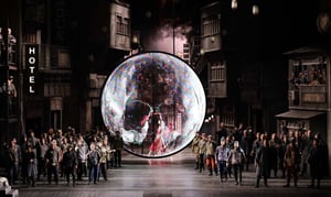 Sul palcoscenico del Teatro alla Scala di Milano è in scena l'opera Turandot, nella foto si vedono gli attori disposti ai fianchi di un ledwall tondo semitrasparente mentre sullo sfondo una scenografia in parte reale ed in parte proiettata da un grande ledwall riproduce una via di Pechino di notte